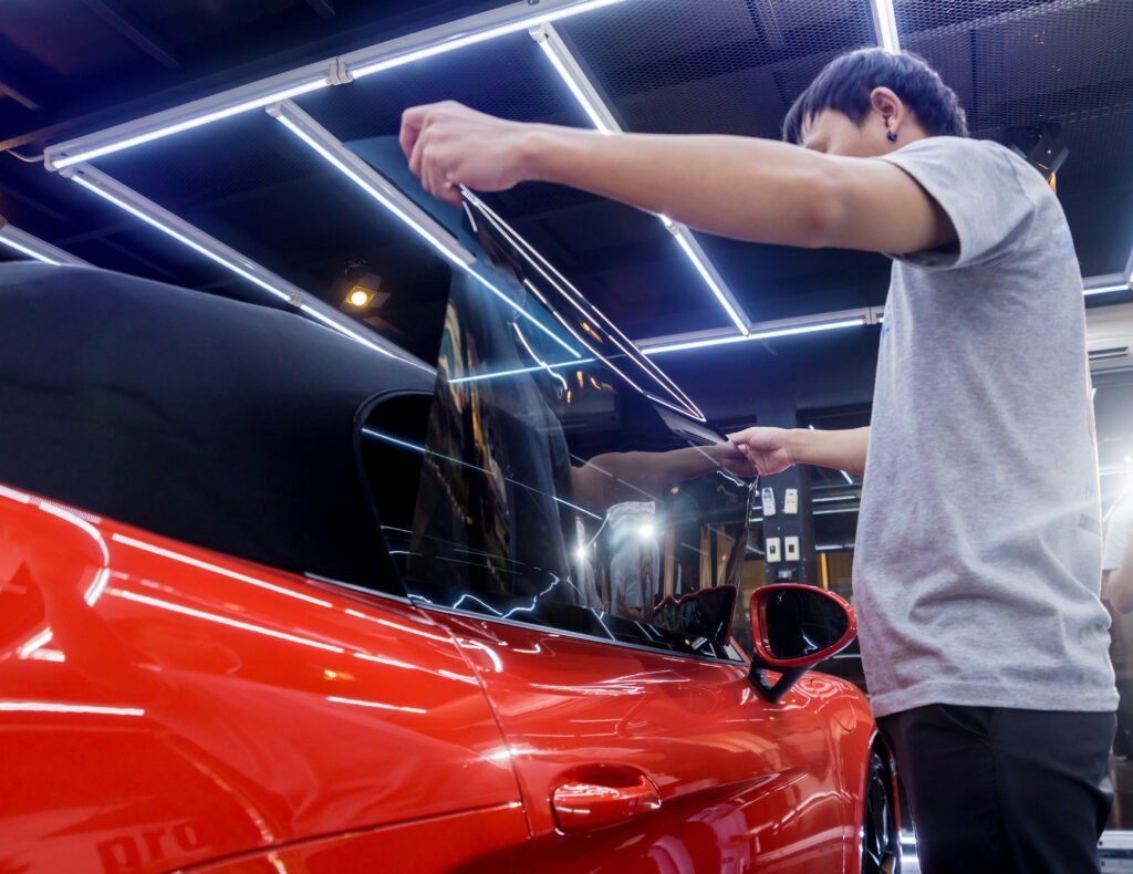 Applying tinting foil on a car window in a auto service